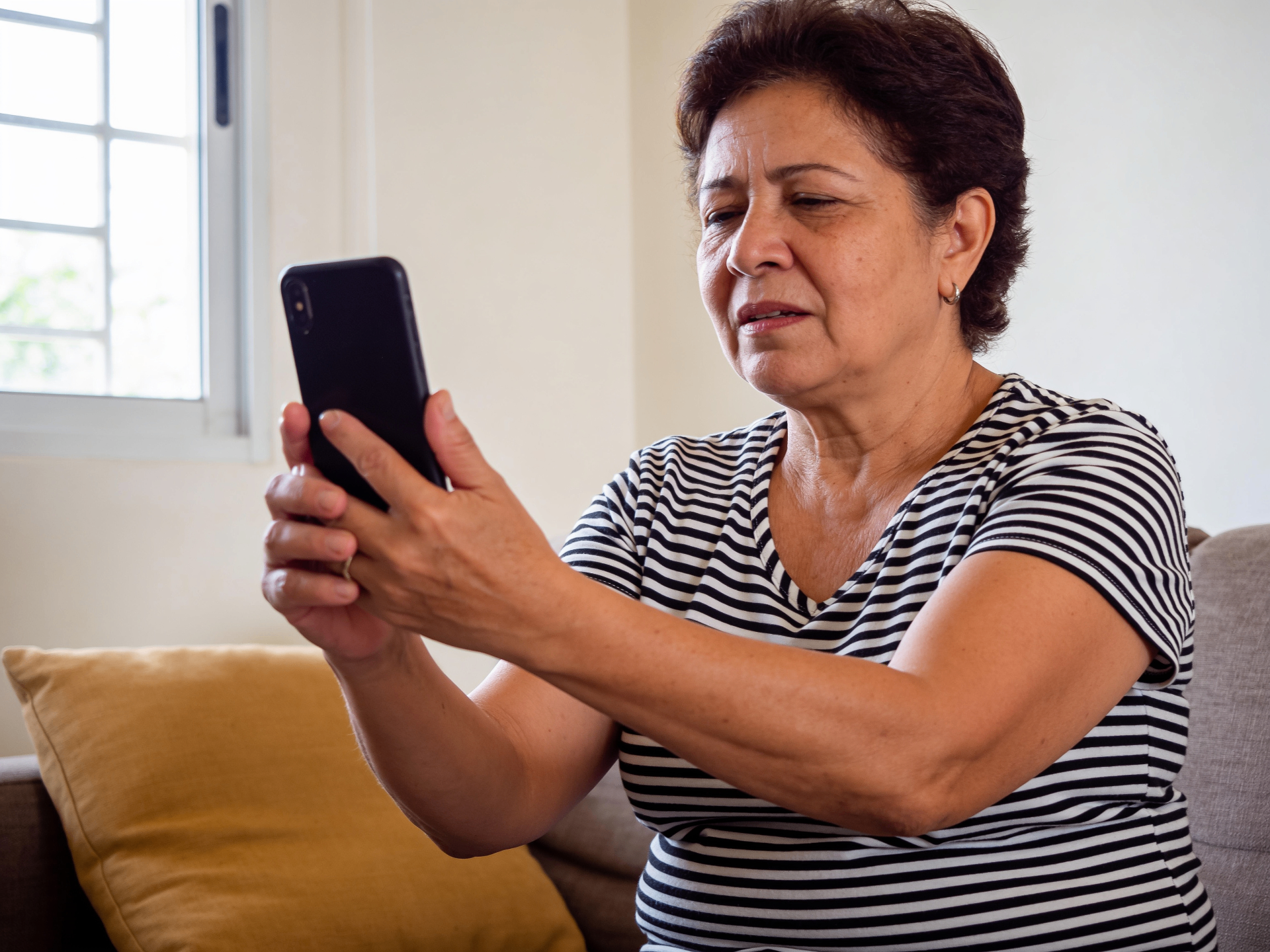 Mulher madura forçando a visão ao olhar o celular